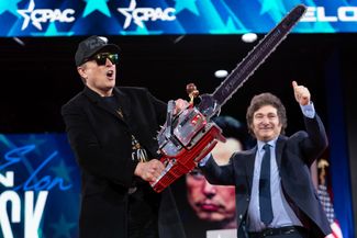 Илон Маск и президент Аргентины Хавьер Милей на Конференции консервативного политического действия (CPAC) в Оксон-Хилле, Мэрилэнд, 20 февраля 2025 года. После того как Маск появился на сцене, Милей преподнес ему подарок — красную бензопилу с гравировкой «Viva la libertad, carajo» («Да здравствует свобода, черт возьми»). «Это бензопила для бюрократии», — сказал Милей. Ранее бензопила стала символом проводимых Милеем шоковых экономических реформ в Аргентине