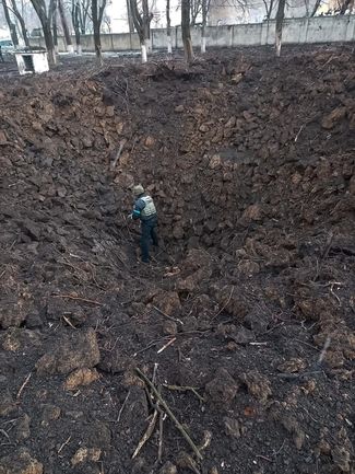 Сапер стоит на дне воронки, оставшейся после очередного удара по Мариуполю. 9 марта 2022 года
